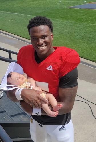 Dexter Williams II holding his daughter on the football field